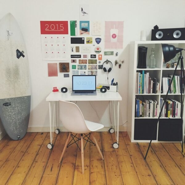White surfboard beside white wall white wooden cube bookshelf inside the room